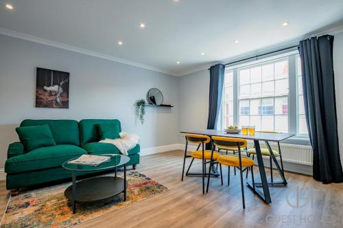 a living room with a green couch and a table at Guest Stays - Bridge Street Apartment in Evesham