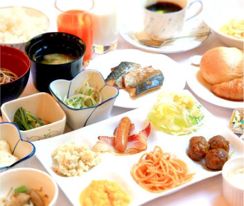 a table with plates of food and bowls of food at Hotel Crown Hills Niigata in Niigata
