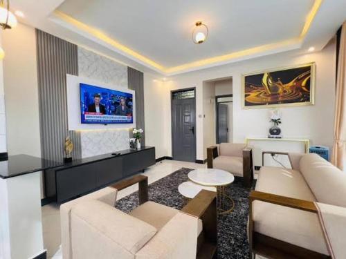 Il comprend un salon doté d'un mobilier blanc et d'une télévision. dans l'établissement Anyiese Homes and Getaways, à Kampala