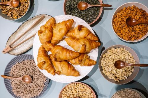 a table topped with plates of pastries and bowls of food at Aria Life Hotel Pinzolo in Pinzolo
