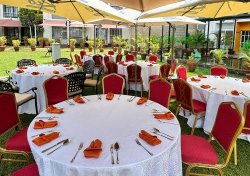 a group of tables with orange napkins and silverware at Rio Eco Gardens Hotel in Nairobi