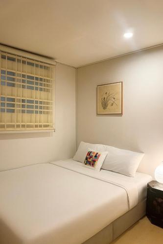 a bedroom with a white bed and a window at Yellow stay in Bucheon