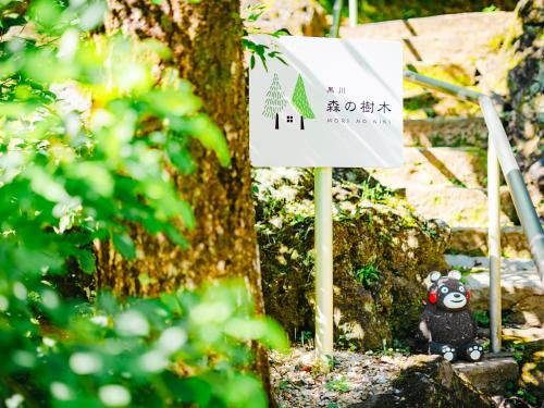 a sign in front of a tree with a panda bear at Kurokawa Mori No Kiki in Minamioguni