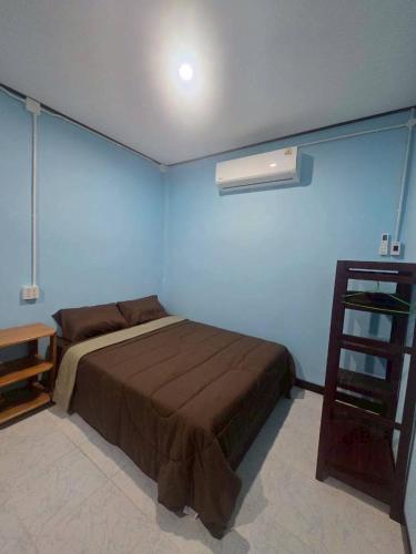 a bedroom with a bed and a blue wall at Mook Lucky family in Ban Chao Mai