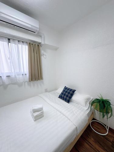 a bedroom with a white bed with a blue pillow and a window at Katsu hotel 3号机场直通 in Osaka