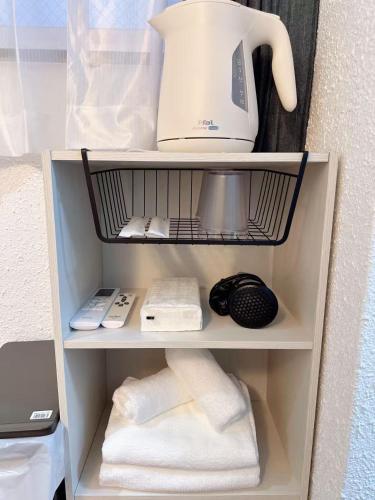 a shelf with a coffee maker and towels on it at Katsu hotel 3号机场直通 in Osaka
