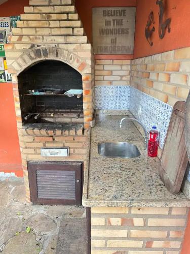 a kitchen with a brick oven with a sink at refugio buzios in Búzios