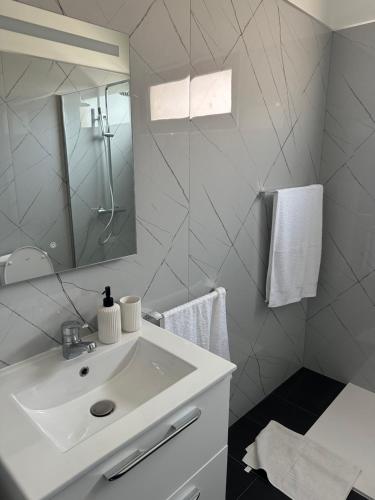 een witte badkamer met een wastafel en een spiegel bij Apartamentos Amarelo in Caniçal