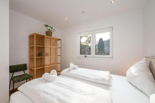a white bedroom with two beds and a window at Drei Berge Blick - by myNests in Gröbming