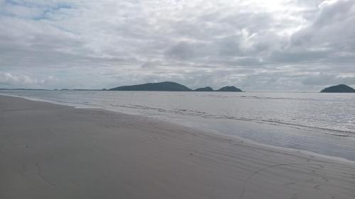 ein Sandstrand mit Bergen in der Ferne in der Unterkunft KitNet suíte Balneário shangrila in Pontal do Paraná