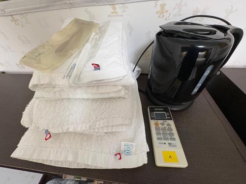 a pile of towels and a remote control on a table at ゲストハウス宮崎 guesthouse miyazaki バックパッカー向け個室旅人宿 P有宮崎駅1km喫煙者不可 in Miyazaki