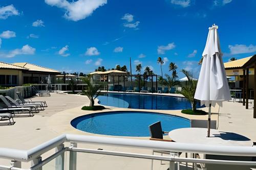 una piscina con ombrellone, tavolo e sedie di Village Baixio Frente ao mar a Baixio