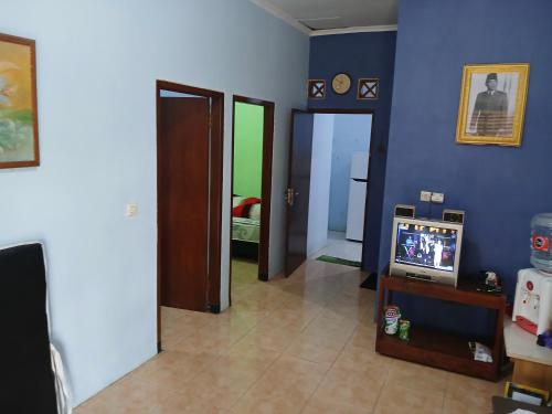 a living room with a tv and blue walls at Mangga in Sengkaling