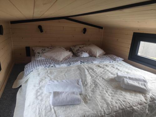 a large bed in a room with white sheets and pillows at Tiny House Barujec in Brenna