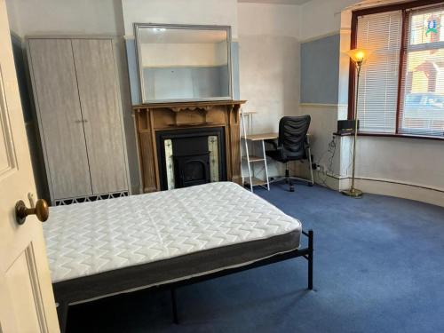 een slaapkamer met een bed, een open haard en een bureau bij Lennox Road Small Rooms Inn in Bletchley