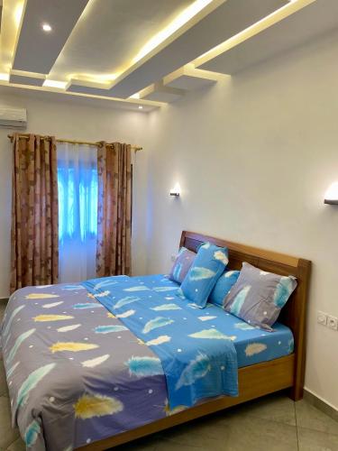 a bedroom with a bed with blue sheets and pillows at Résidence Prestige KGV Appt 201 in Douala