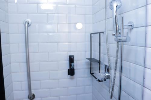 un bagno con doccia e piastrelle bianche di IBIS PRIMAVERA DO LESTE a Primavera do Leste