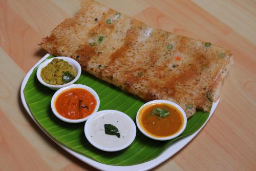 een bord met eten, een sneetje brood en sauzen bij Thekkady Arasi Hotel in Thekkady