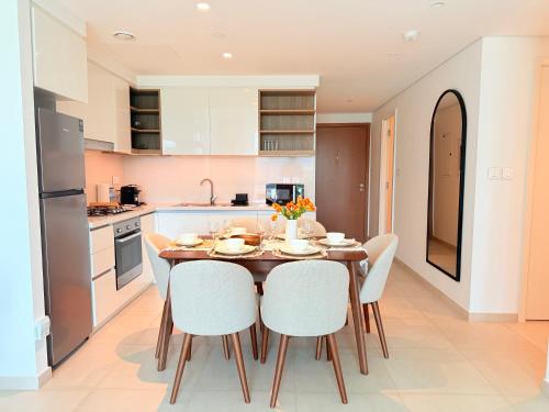 a kitchen with a wooden table and white chairs at Private Room in Luxury Burj Vista Apartment Downtown with Burj Khalifa View in Dubai