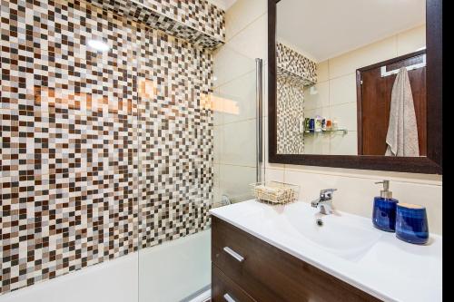 une salle de bain avec un lavabo et une douche avec un miroir dans l'établissement Casa do Mar, à Sesimbra