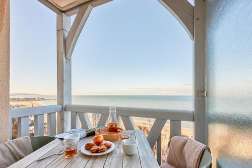 a table with a plate of fruit and a view of the ocean at Résidence Pierre & Vacances Les Tamaris in Trouville-sur-Mer