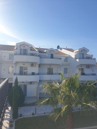 een groot wit gebouw met palmbomen ervoor bij Resort Comfort Long Beach in Ulcinj