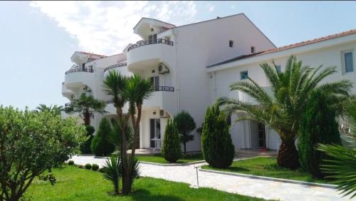 een groot wit gebouw met palmbomen ervoor bij Resort Comfort Long Beach in Ulcinj