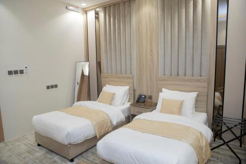 two beds in a hotel room with white sheets at بن سنكر لشقق المخدومة in Sharurah