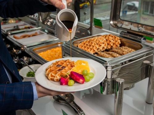 eine Person, die einen Teller mit Essen und ein Glas Wein hält in der Unterkunft Ibis Styles Wroclaw Centrum in Breslau