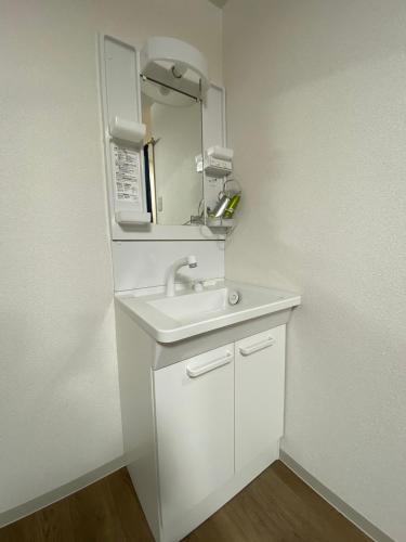 a white bathroom with a sink and a microwave at 民宿一休 in Otaru