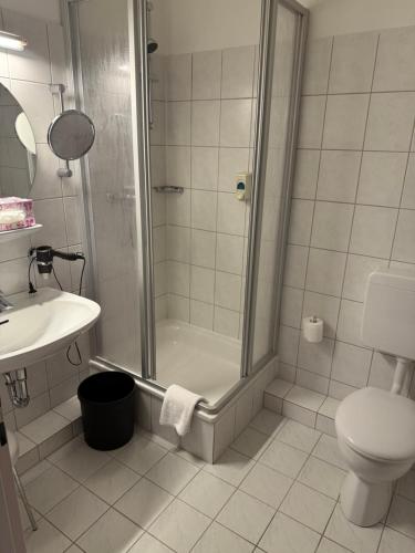 a bathroom with a shower and a toilet and a sink at Hotel Krohwinkel in Hittfeld