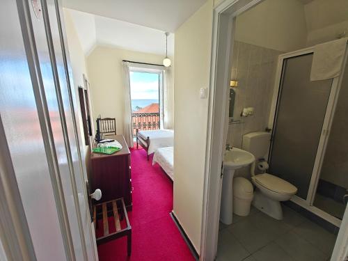 een badkamer met een wit toilet, een wastafel en een bad bij Mirasol Guesthouse in Funchal