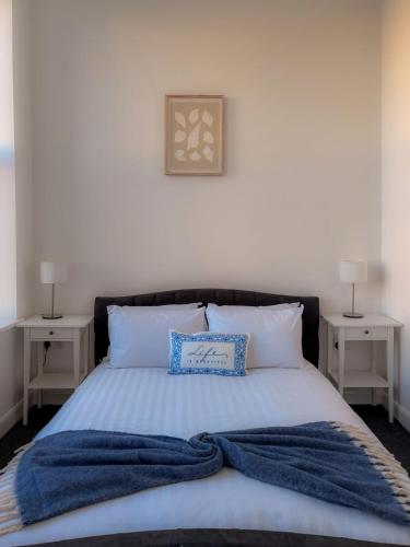 a bed with a blue blanket and two night stands at Euston Road - Beach Apartment 10 in Great Yarmouth