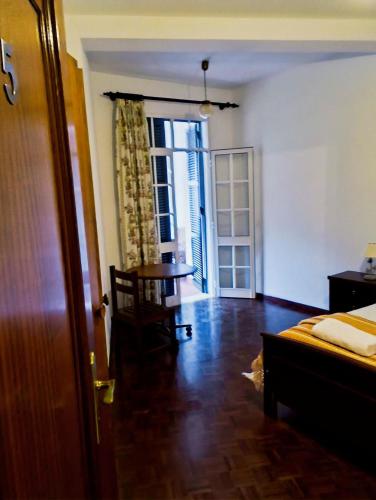 a room with a bed and a table and a door at Narciso's House in São Vicente