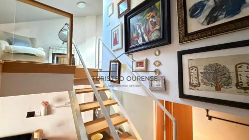 a staircase in a living room with pictures on the wall at Calpurnia Casco Viejo in Ourense