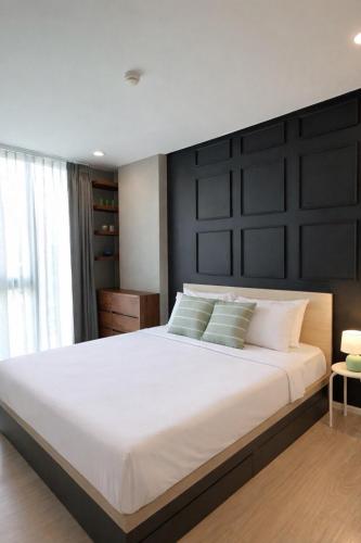 a bedroom with a large white bed with a black headboard at Modern Condo in Nimman 501 in Chiang Mai