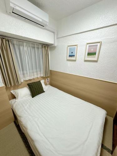 ein Schlafzimmer mit einem großen weißen Bett mit einem Fenster in der Unterkunft Katsu hotel 3号一室一厅 in Osaka