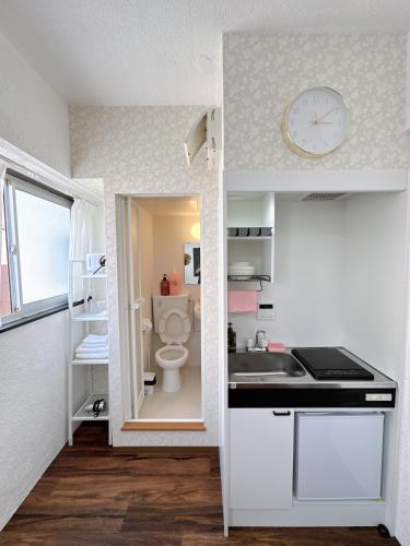 ein kleines Badezimmer mit Toilette und einer Uhr an der Wand in der Unterkunft Katsu hotel 3号一室一厅 in Osaka