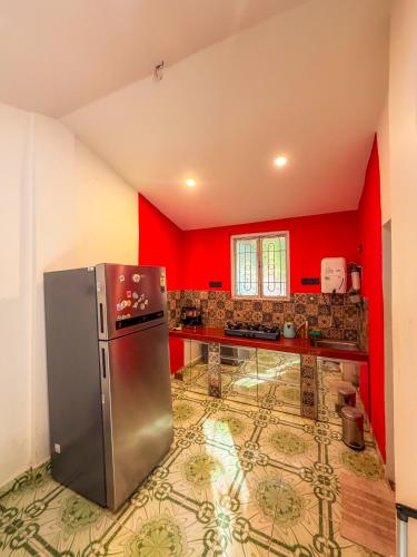 eine Küche mit roten Wänden und einem Kühlschrank aus Edelstahl in der Unterkunft Traverse Homes Palolem in Canacona