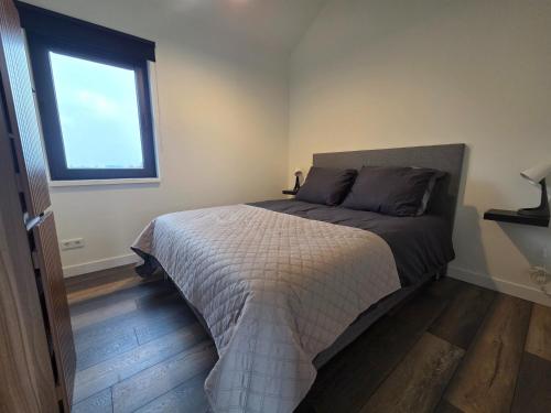 een slaapkamer met een bed en een raam bij Chalet aan het water in Sprong