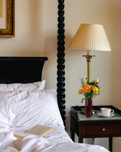 a bed with a lamp and a vase of flowers on a night stand at Bailbrook House Hotel, Bath in Bath