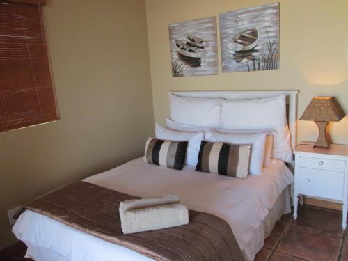 una camera da letto con letto, lenzuola e cuscini bianchi di Point Village Accommodation - Sean's House a Mossel Bay