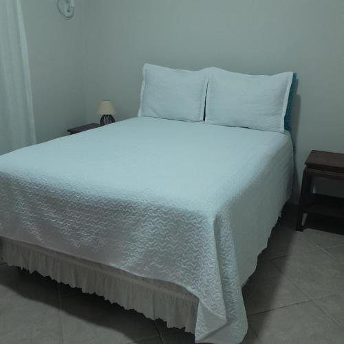 een bed met een witte deken en kussens erop bij Casa Valen com 2 quartos in Rio de Janeiro