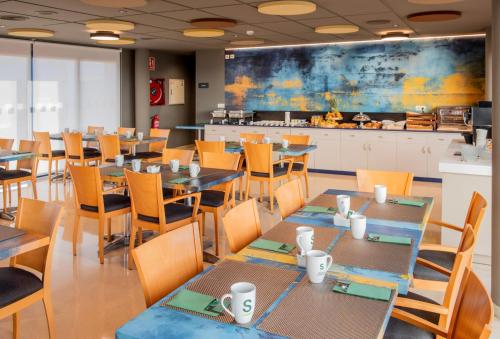 ein Esszimmer mit Tischen und Stühlen und eine Küche in der Unterkunft Hotel Sercotel Plana Onda in Onda