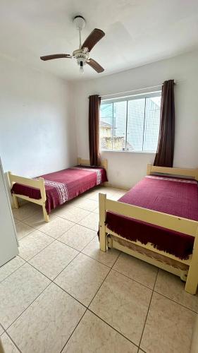 a bedroom with two beds and a ceiling fan at Residencial Da Cal in Torres
