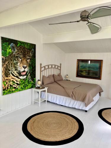 a bedroom with a bed and a painting of a leopard at Piesang Valley Cottage Djungle in Plettenberg Bay
