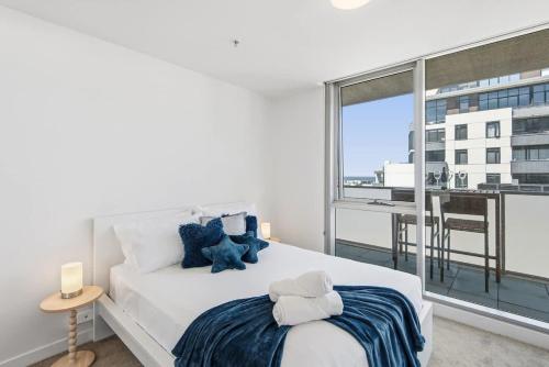 a bedroom with a large white bed and a large window at 2BR Port Melbourne apt - 2 min walk from beach in Melbourne
