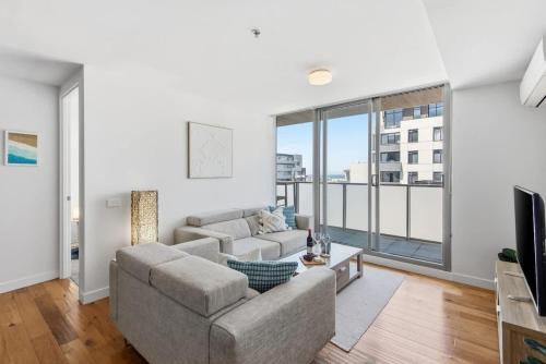 a living room with a couch and a large window at 2BR Port Melbourne apt - 2 min walk from beach in Melbourne