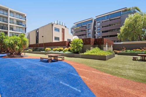 a park with two benches and some buildings at 2BR Port Melbourne apt - 2 min walk from beach in Melbourne