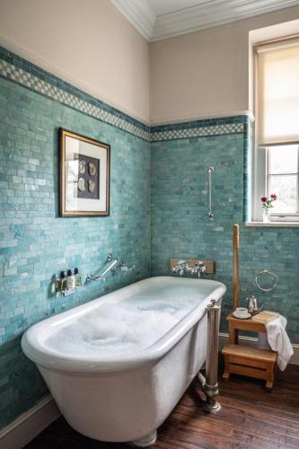 a bath tub in a bathroom with blue tiles at Crathorne Hall in Yarm